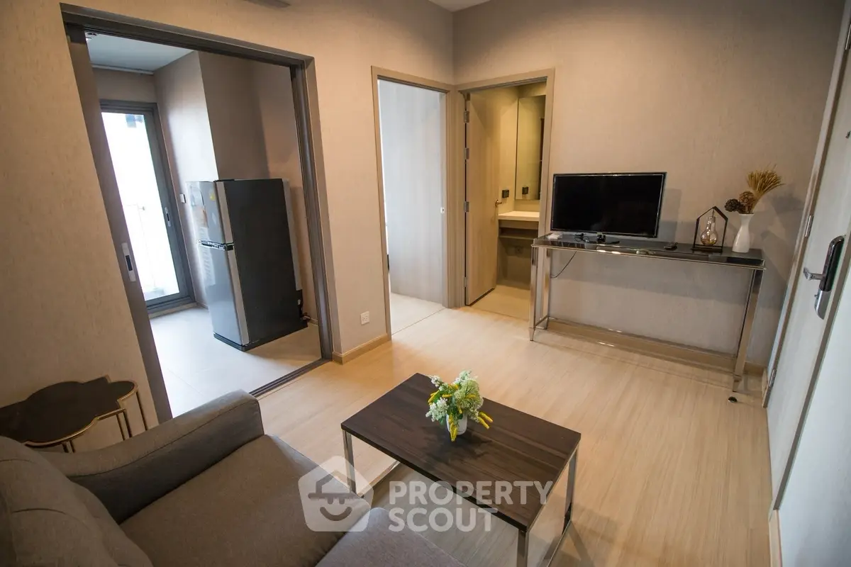 Modern living room with sleek furniture and open kitchen layout in a stylish apartment.