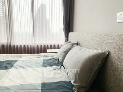 Cozy bedroom with modern decor and large window offering natural light.