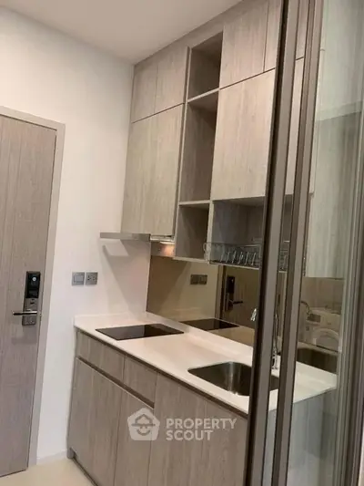 Modern compact kitchen with sleek cabinetry and built-in appliances in a stylish apartment.