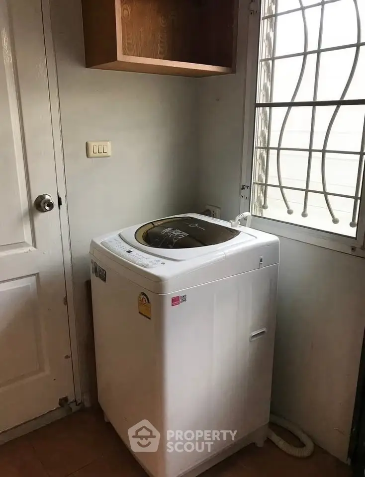 Compact laundry area with top-load washing machine and wall cabinet