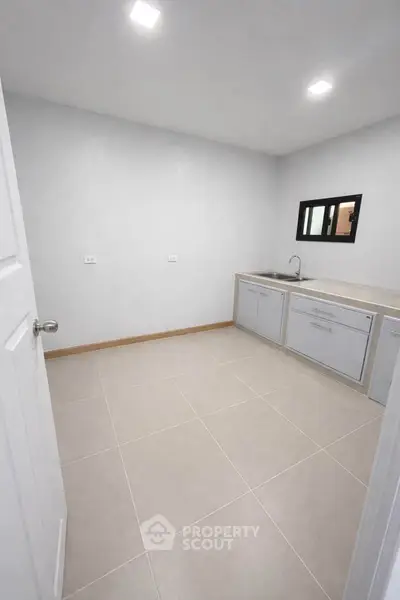 Spacious kitchen with modern cabinetry and sleek tile flooring, perfect for culinary enthusiasts.