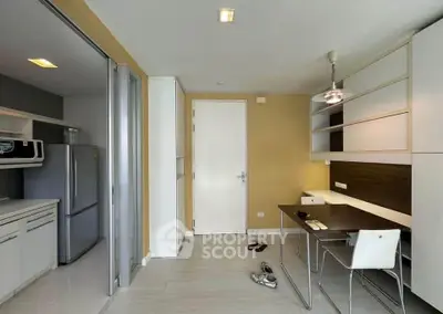 Modern apartment interior with kitchen and study area, featuring sleek design and ample storage.