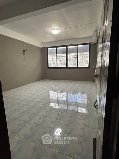 Spacious empty room with large windows and tiled flooring, perfect for customization.