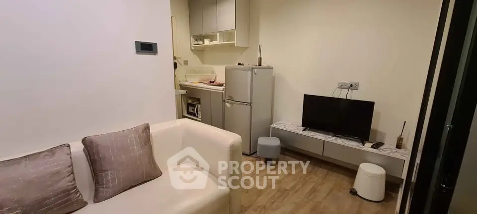 Cozy living room with modern kitchenette and compact fridge in a stylish apartment.