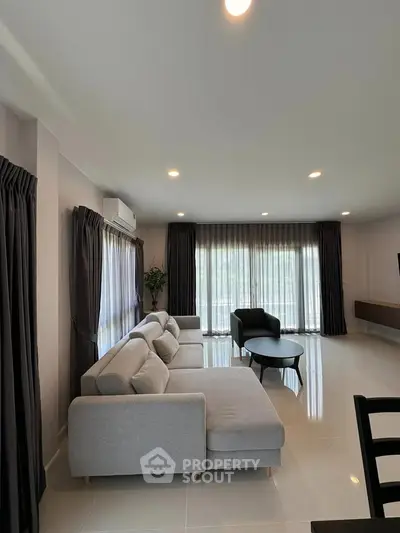 Spacious modern living room with elegant gray sofa and large windows.