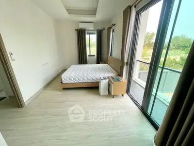 Spacious bedroom with balcony and large windows offering natural light and scenic views.