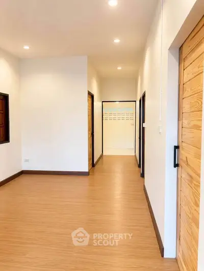 Spacious hallway with wooden flooring and modern lighting in a contemporary home.