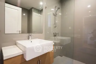 Modern bathroom with sleek glass shower and stylish sink in contemporary apartment.