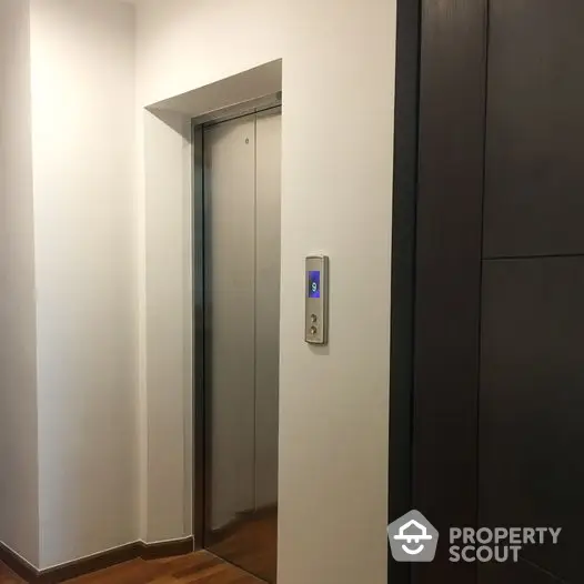 Modern elevator in a sleek residential building with wooden flooring and minimalist design.