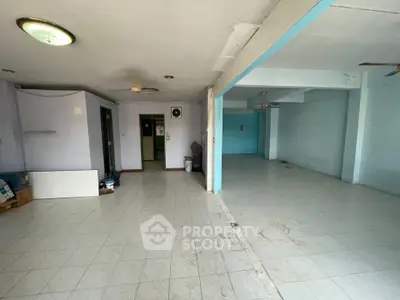 Spacious open-plan interior with tiled flooring and ceiling fans, ideal for versatile use.