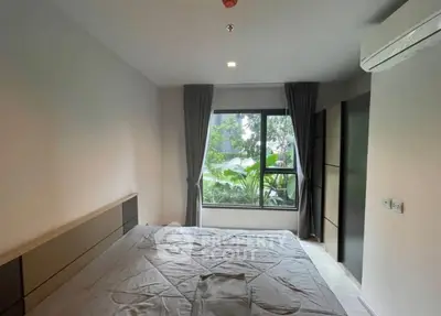 Spacious bedroom with large window and garden view, featuring modern decor and air conditioning.