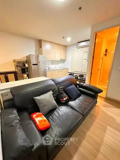 Modern open-layout living room with sleek kitchen and cozy leather sofa, perfect for urban living.