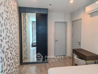 Modern bedroom with stylish wallpaper and mirrored wardrobe in a cozy apartment.