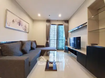 Modern living room with large sofa, glass coffee table, and city view from window.