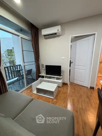 Cozy living room with balcony access, featuring modern furniture and wooden flooring.