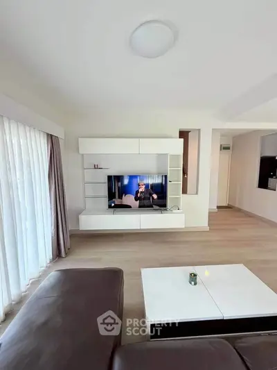 Spacious modern living room with sleek entertainment center and large windows for natural light.