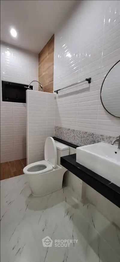 Modern bathroom with sleek design, featuring a white toilet, sink, and stylish tile accents.