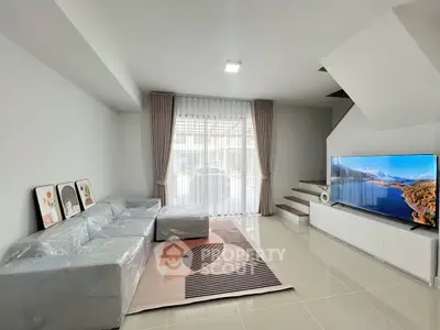 Modern living room with sleek furniture and large TV, perfect for relaxation and entertainment.