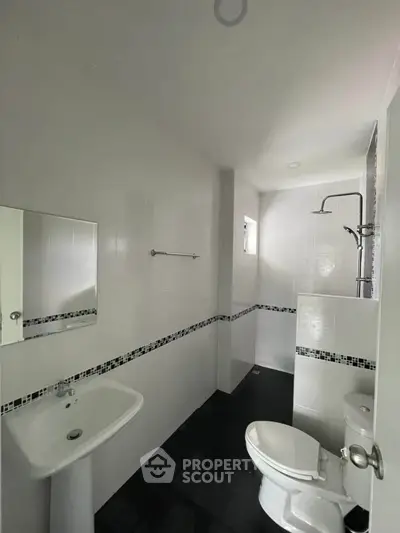 Modern bathroom with sleek white tiles and a compact shower area.