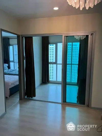 Elegant bedroom with large mirrored closet doors and direct balcony access, showcasing modern design and a glimpse of the cityscape.