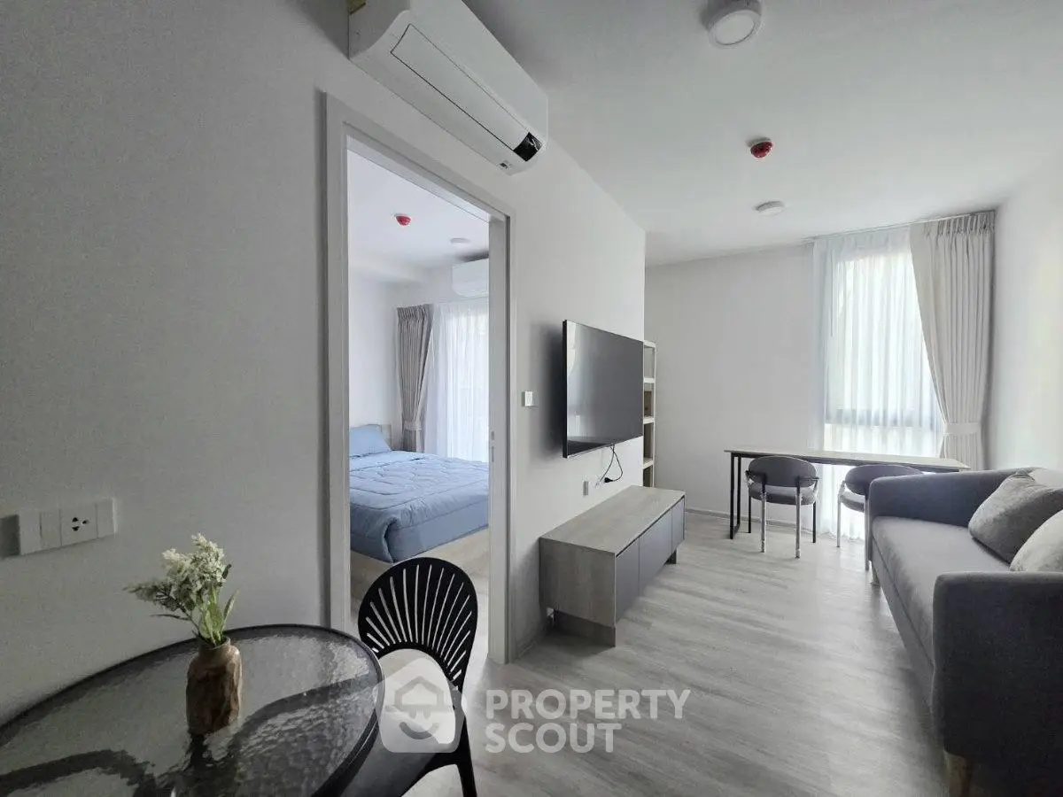 Modern living room with sleek furniture and natural light, featuring a cozy bedroom view.