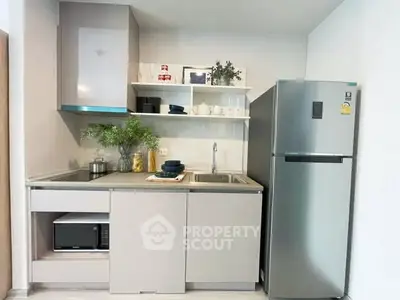 Modern kitchen with sleek cabinetry, stainless steel fridge, and open shelving for stylish storage.