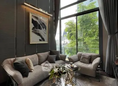 Luxurious living room with modern decor and large windows offering a stunning view of greenery.