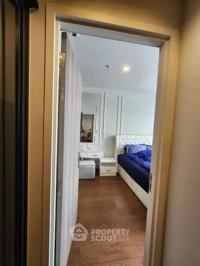 Elegant bedroom with wooden flooring and plush bed, showcasing modern interior design.