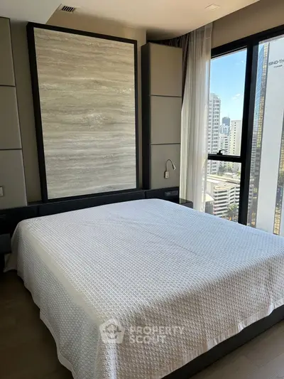 Luxurious bedroom with city view and modern decor in high-rise apartment.