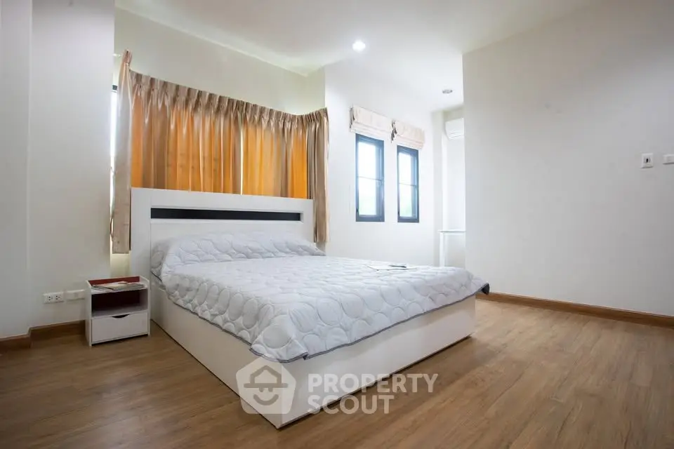 Spacious bedroom with modern design and natural light, featuring elegant wooden flooring and stylish decor.