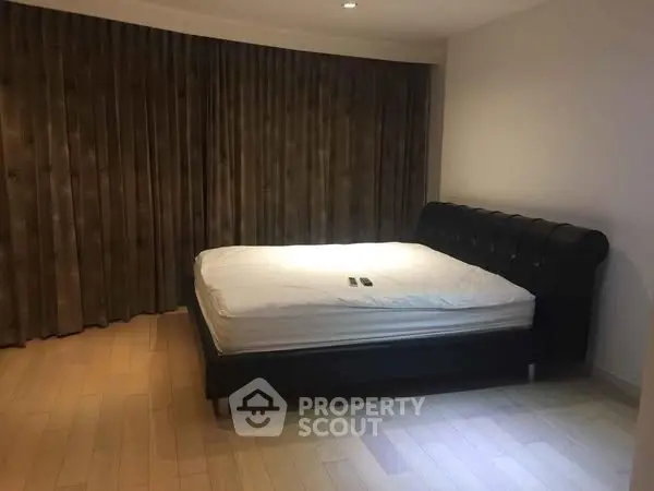 Spacious bedroom with elegant bed and wooden flooring in modern apartment.