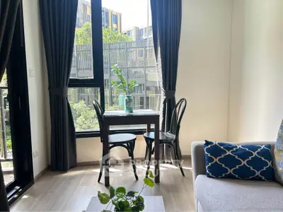 Bright living room with modern decor and large windows overlooking greenery.
