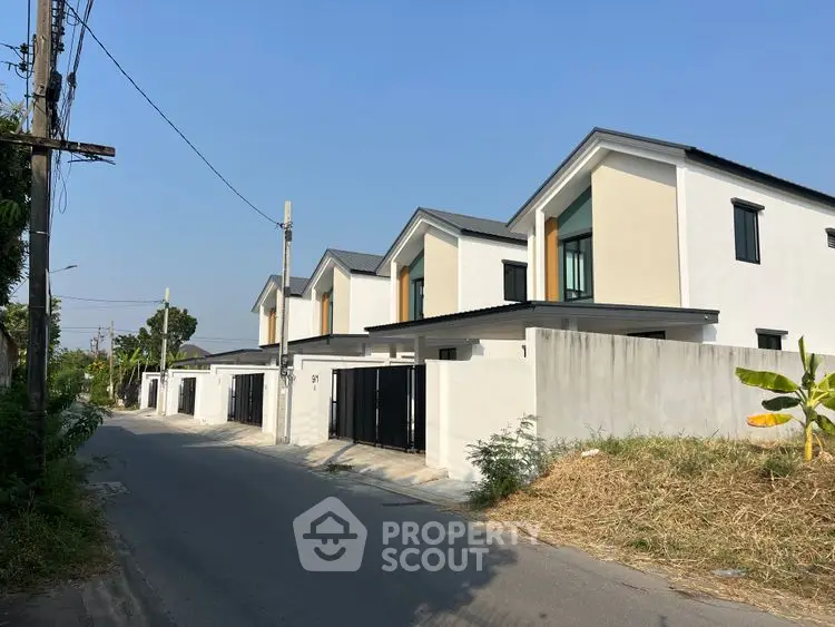 Modern row of townhouses with sleek design and gated entrances on a sunny day.