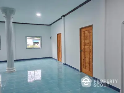 Spacious interior with blue tiled floor and wooden doors, featuring a decorative column.