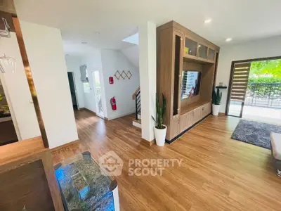 Spacious modern living room with wooden flooring and large windows opening to a balcony.