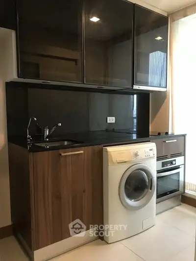 Modern kitchen with sleek cabinetry, built-in oven, and washing machine, perfect for urban living.