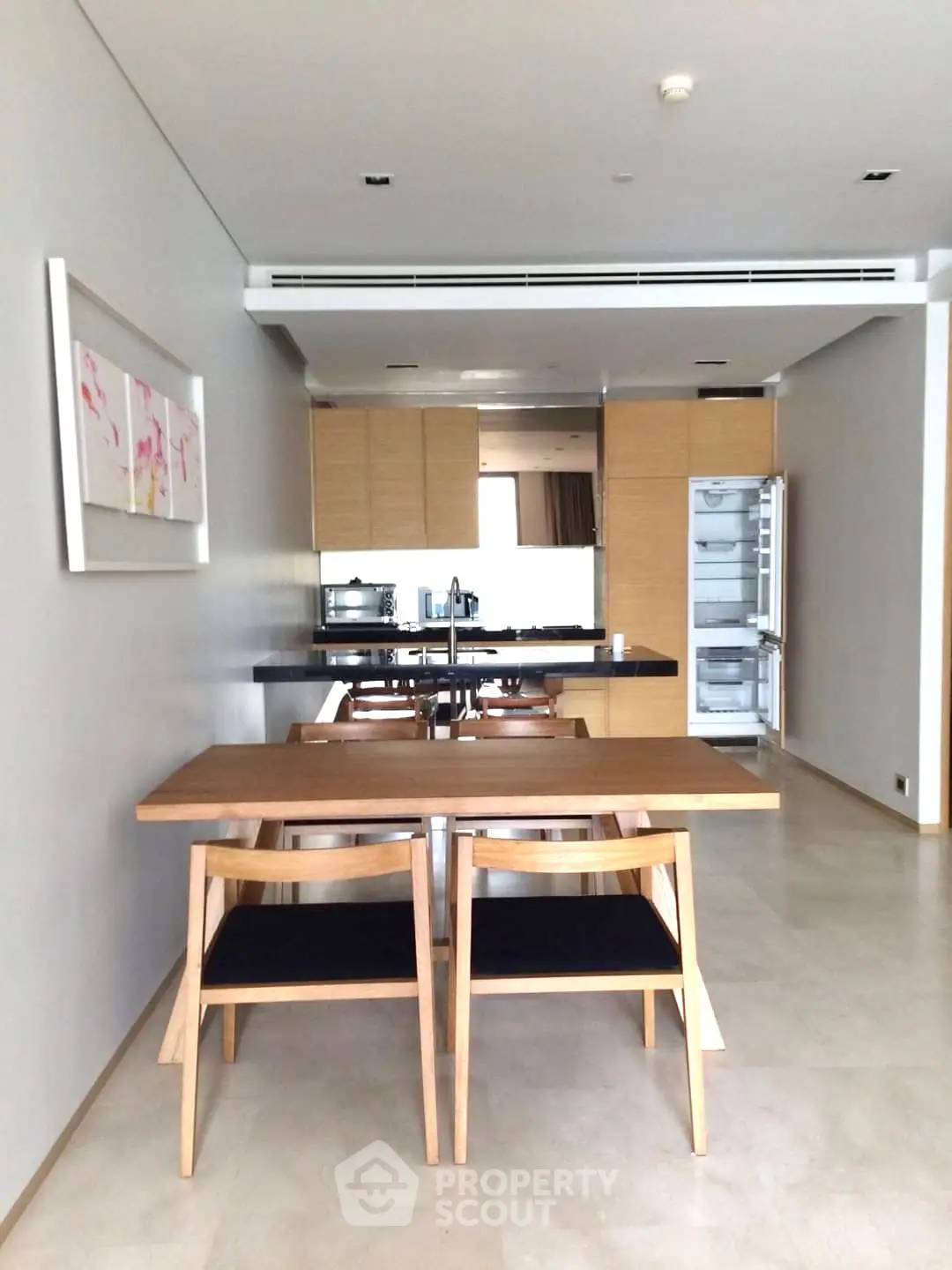 Modern open kitchen with wooden dining table and chairs, sleek cabinetry, and built-in appliances.