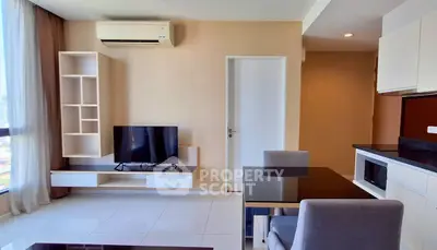 Modern living room with sleek furniture and natural light, featuring a TV and air conditioning.