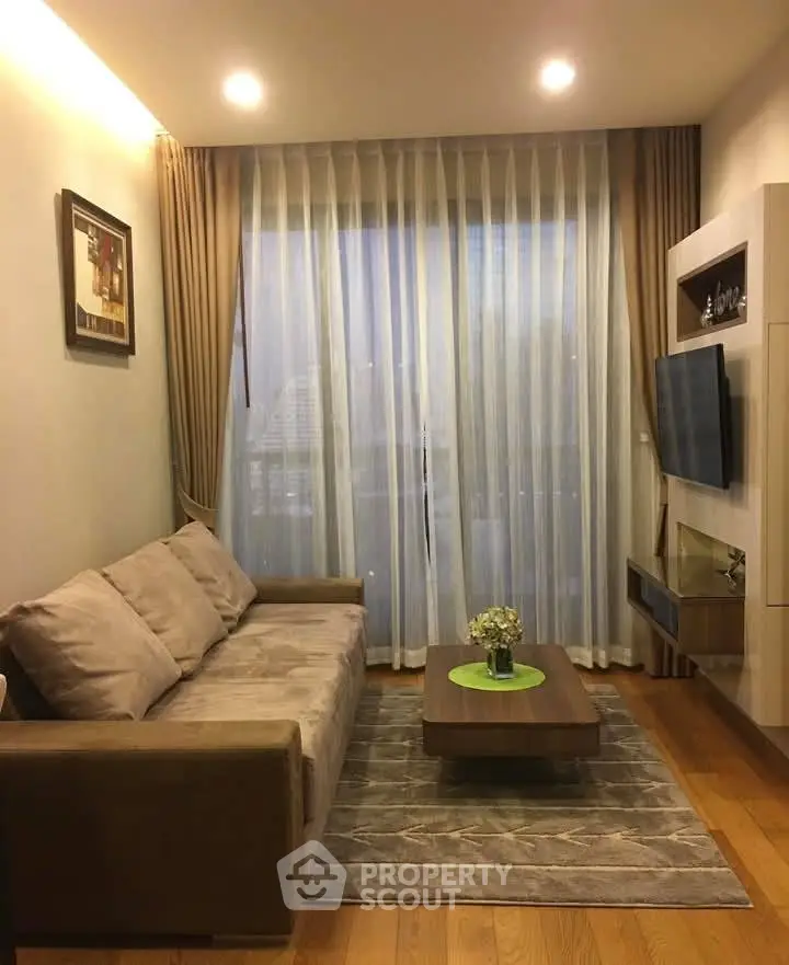 Cozy living room with modern decor, featuring a plush sofa, wall-mounted TV, and elegant curtains.