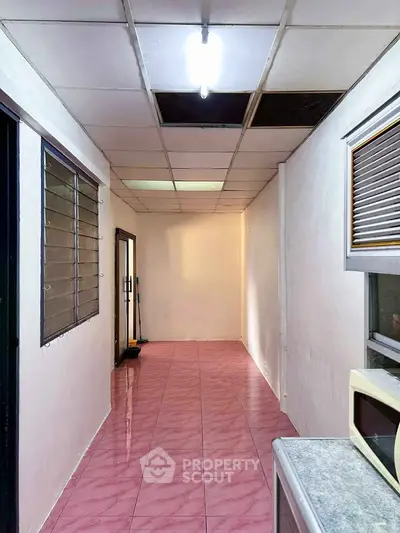Spacious hallway with pink tiled floor and bright lighting, ideal for versatile use.