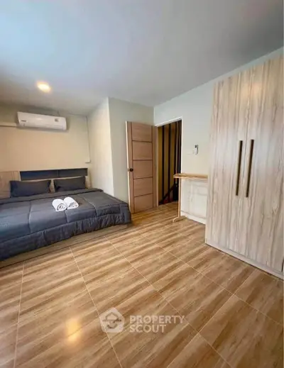 Modern bedroom with wooden flooring and sleek wardrobe design.