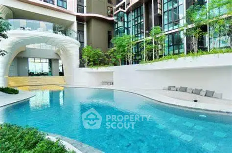 Luxurious modern apartment complex with stunning pool and lush greenery.