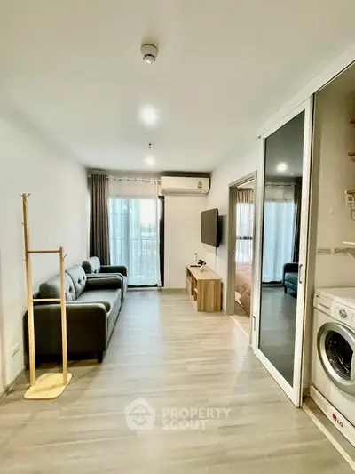 Modern living room with sleek furniture and washing machine, featuring a balcony view.