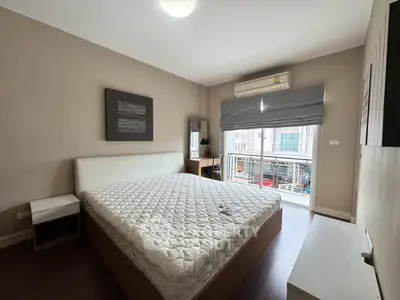 Spacious bedroom with large window and modern furnishings in a stylish apartment.