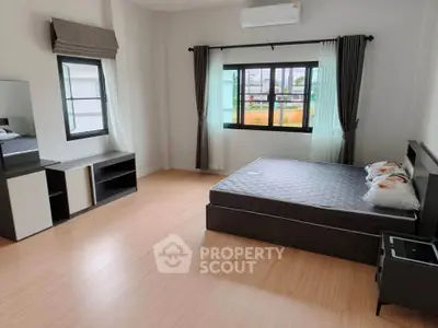 Spacious bedroom with modern furnishings and large windows for natural light.