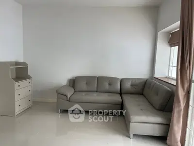 Spacious living room with modern gray sectional sofa and natural light.