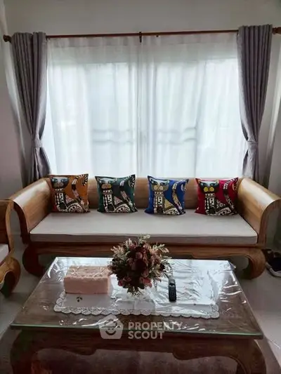 Charming living room with elegant wooden sofa and colorful cushions, perfect for cozy gatherings.