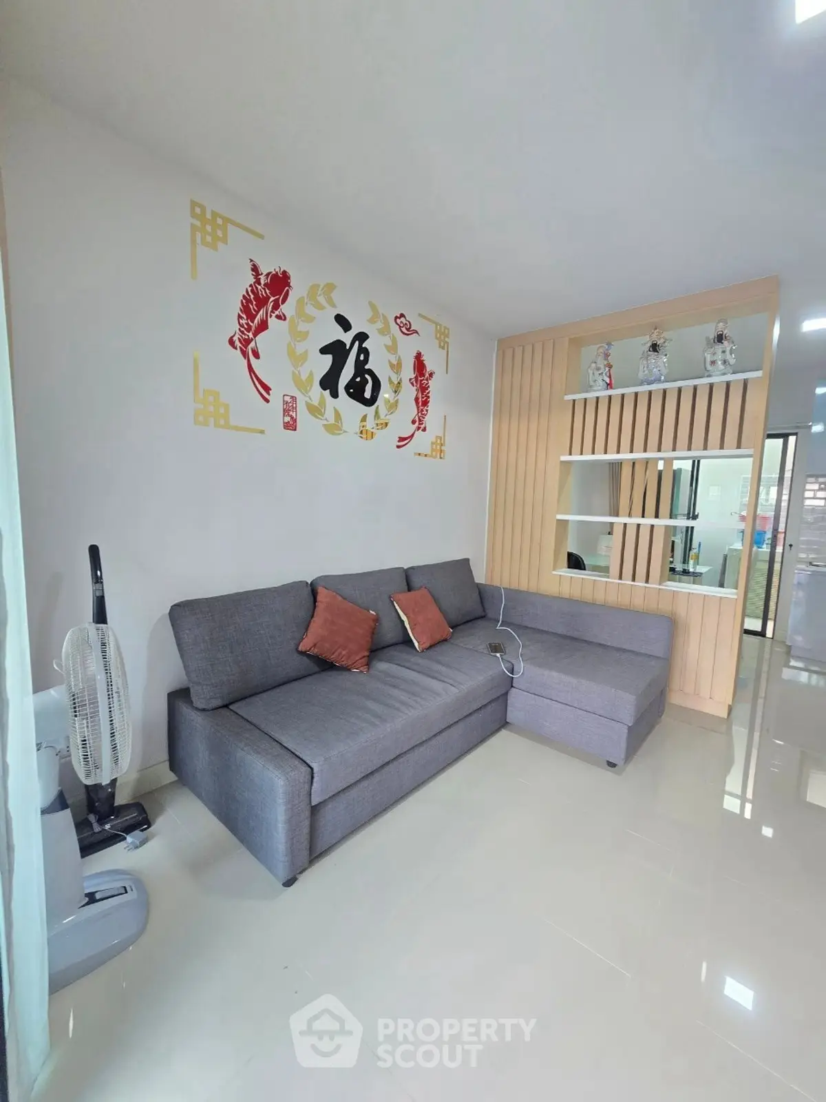 Modern living room with stylish gray sofa and decorative wall art, featuring sleek shelving and glossy tiled flooring.