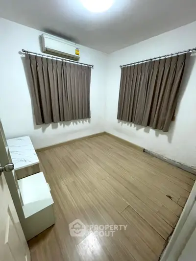 Spacious unfurnished bedroom with wooden flooring and air conditioning, perfect for customization.