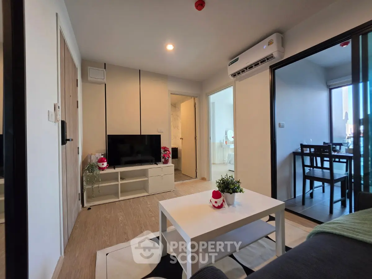 Modern living room with sleek furniture and air conditioning, adjacent to a dining area with natural light.